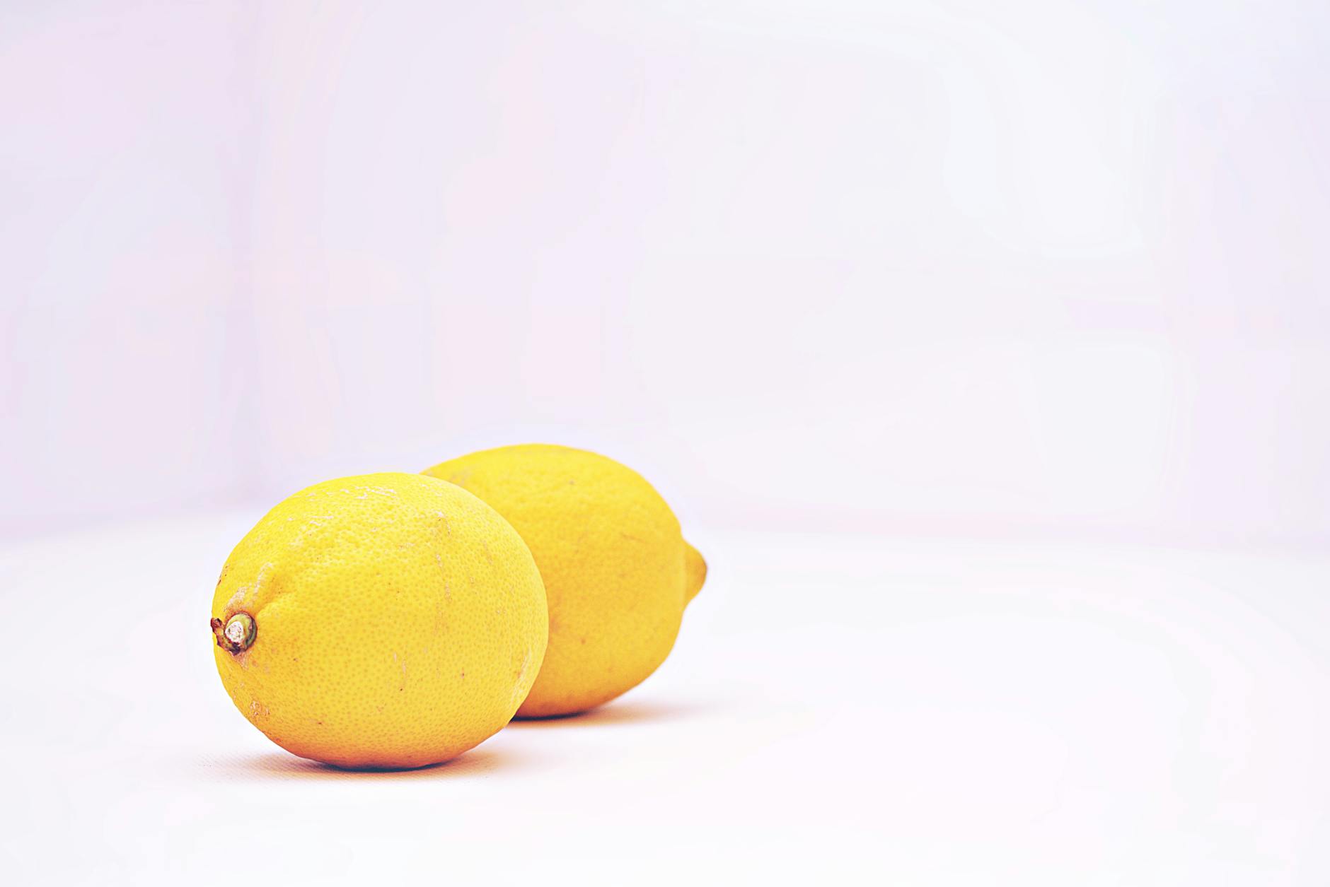Two vibrant lemons on a white background, representing freshness and the Lemon Clit Online philosophy
