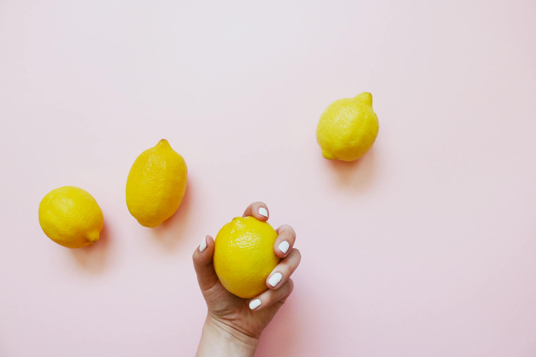 A hand holding an orange vibrator against a minimalistic purple backdrop