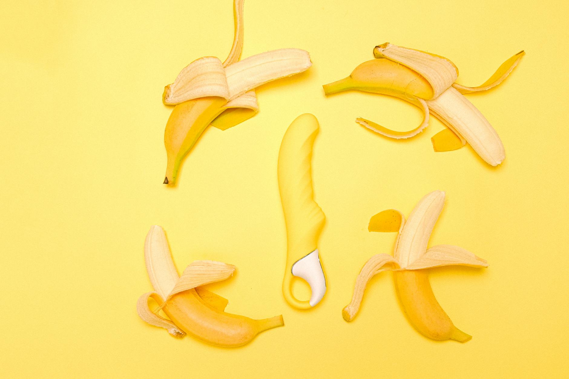 Yellow silicone lemon clitoral vibrator on a bright yellow background with fresh lemons