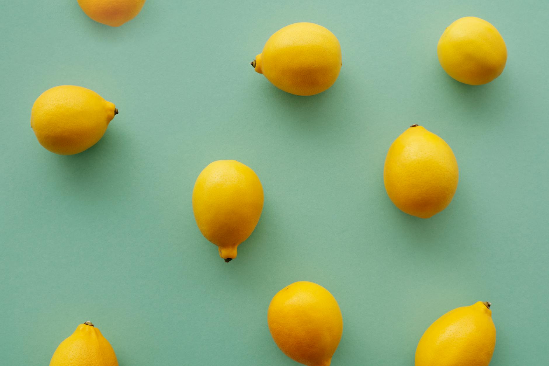 Bright yellow lemons arranged on a pastel green background, symbolizing fresh starts and gentle renewal