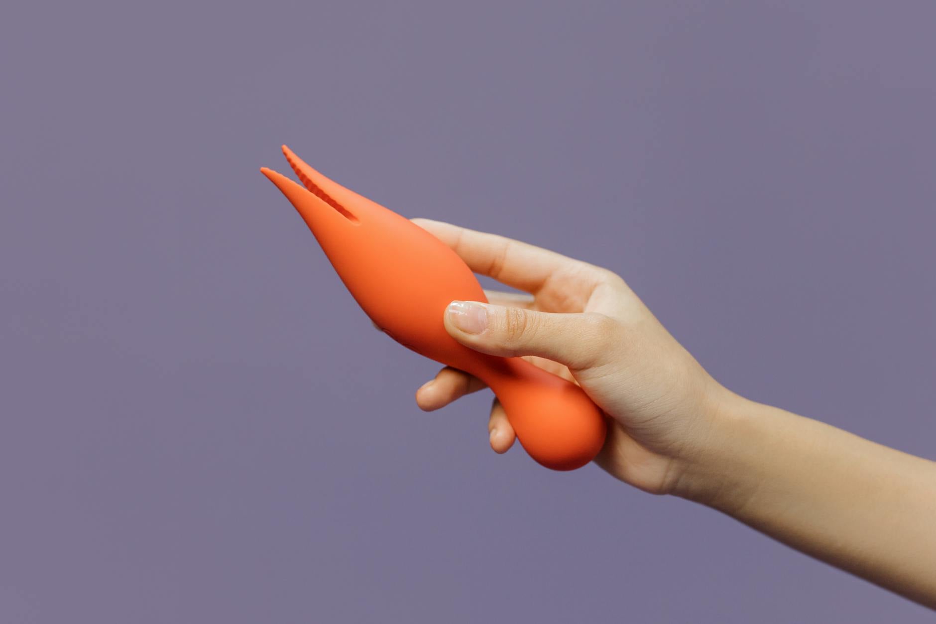 A hand holding a vibrator, showcasing intentional pleasure and self-care.