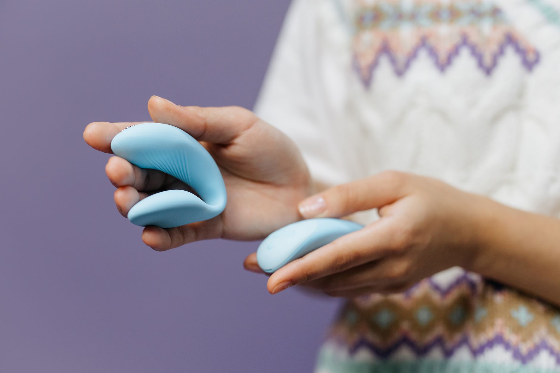 Close-up of hands holding a sleek blue vibrator, representing reconnection with pleasure