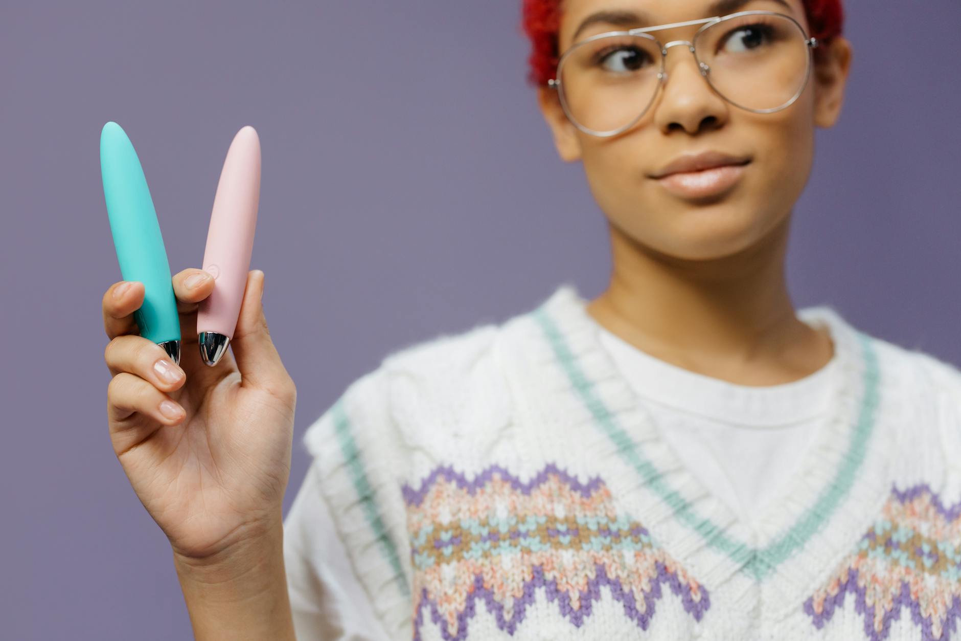 Woman holding colorful vibrators demonstrating pleasure tools
