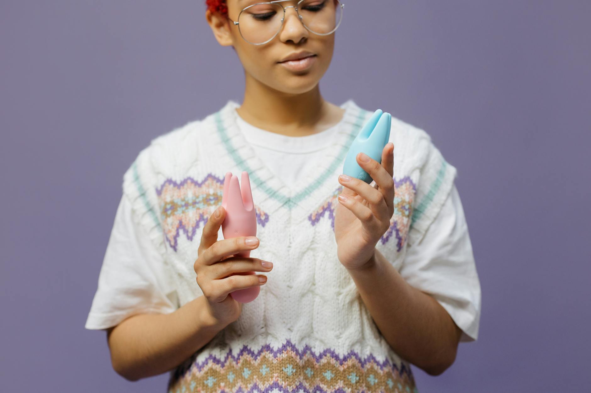 Woman holding blue and pink silicone vibrators with a contemplative expression, representing courage in new partnerships.