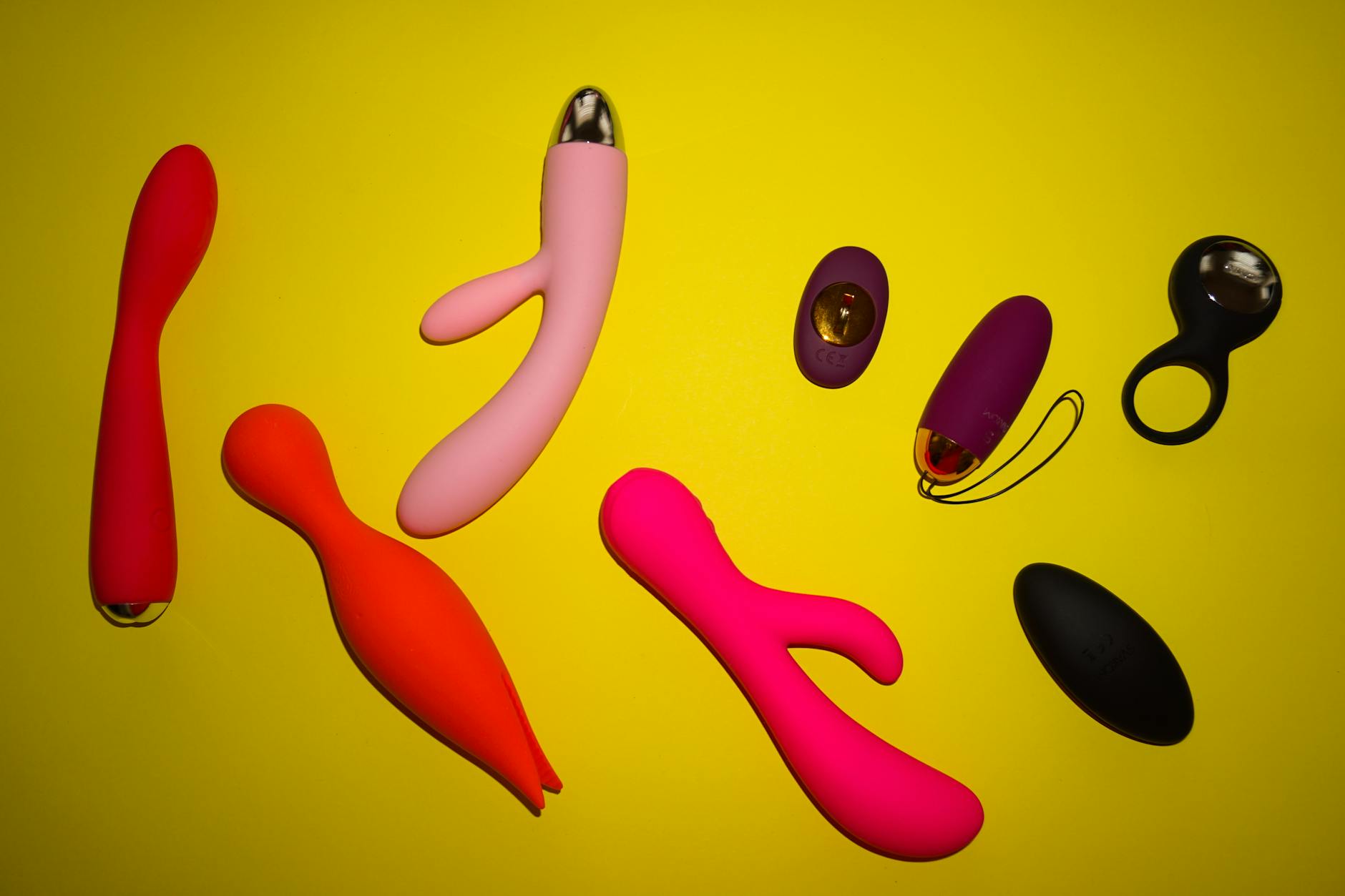 Colorful vibrators and adult toys arranged on bright yellow background