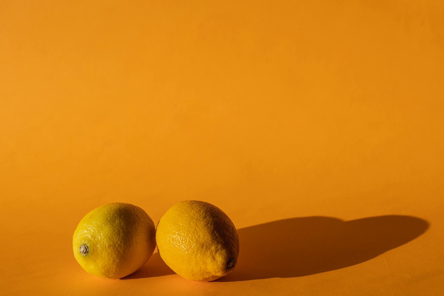 A blue vibrator surrounded by flowers and citrus on a yellow background, representing pleasure and reconnection with your body